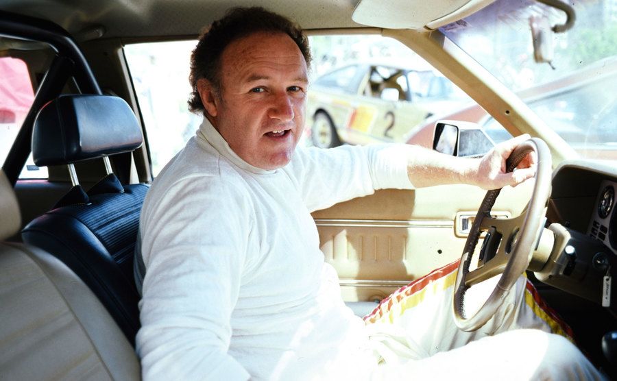 A photo of Hackman driving a car.