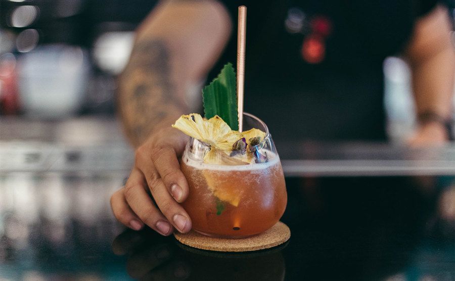 A bartender hands over a cocktail. 