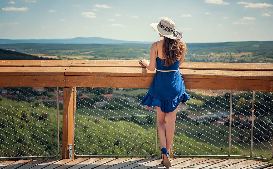 A woman in a blue dress is looking at he view. 