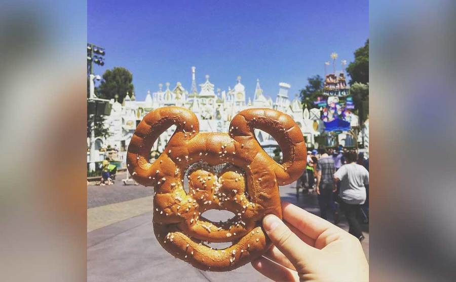 A person holds up a Mickie Mouse shaped pretzel. 