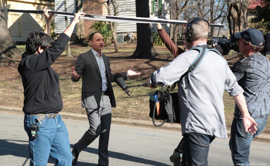 David Visentin is walking and filming with his camera crew. 